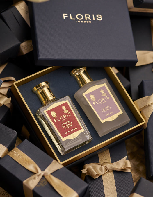 A boxed Cherry Blossom Duet from Floris London, featuring two exquisite perfumed products, nestled in-between beautifully gift wrapped presents. This luxurious gift set is perfect for the holiday season.