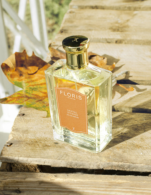 A bottle of 'Santal Intense' surrounded by autumn foliage. 