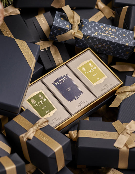 A boxed Soap Collection For Him from Floris London, featuring three exquisite soap products, nestled in-between beautifully gift wrapped presents. This luxurious gift set is perfect for the holiday season.