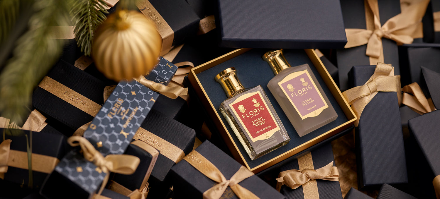 A boxed Cherry Blossom Duet from Floris London, featuring two exquisite perfumed products, nestled in-between beautifully gift wrapped presents. This luxurious gift set is perfect for the holiday season.