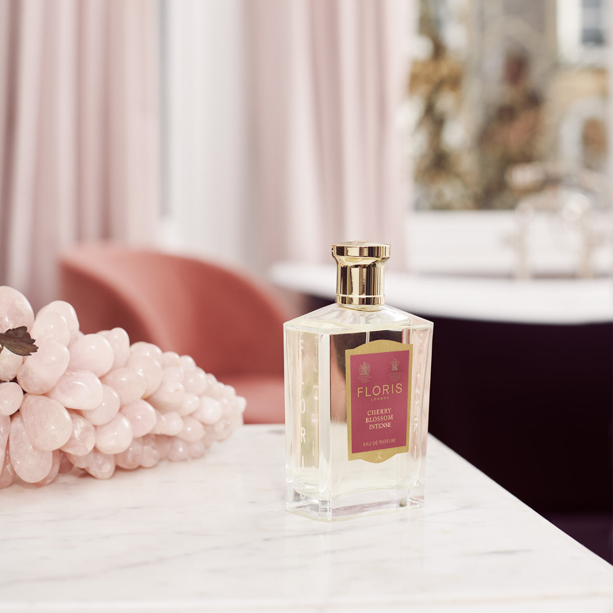 Cherry Blossom Intense by Floris London on a marble table, cherry blossom decor, and an elegant chair in the background.