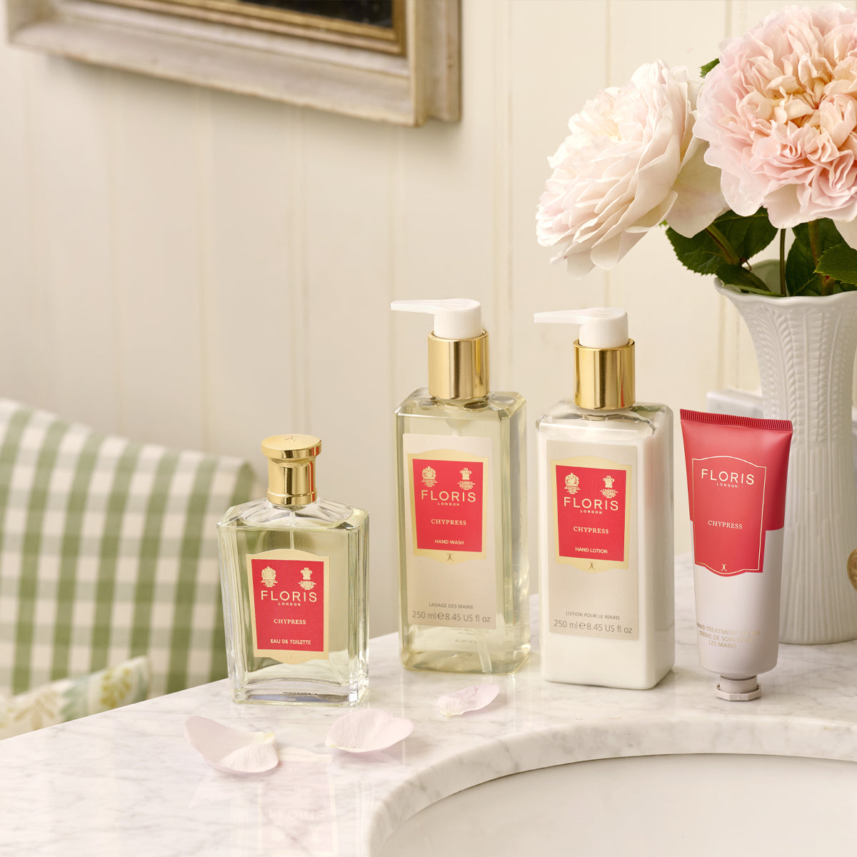 Floris London's Chypress Eau de Toilette on a marble counter with pink roses, white petals, and bergamot zest enhances the arrangement.