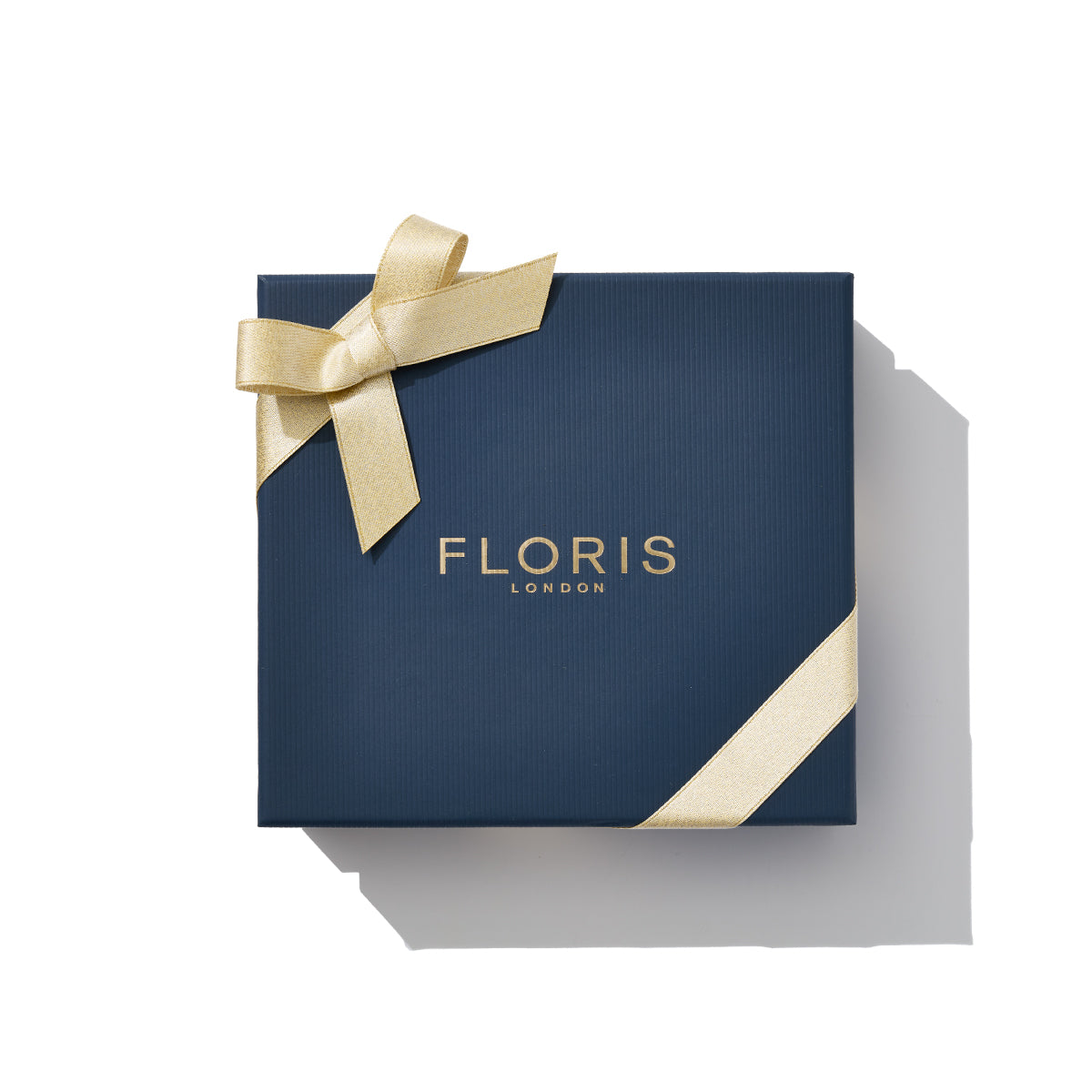 A navy gift box featuring "Floris London" in gold along with a gold ribbon bow, ideal for celebrating the season, containing the Perfumer's Trilogy: For Her.