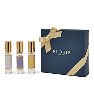 The essence of floral fragrances is elegantly captured by three small perfume bottles, accompanied by a navy blue gift box adorned with a gold ribbon and the "Floris London" logo from the Perfumer's Trilogy: For Her (2024 xmas) collection, making it perfect for the season of celebration.