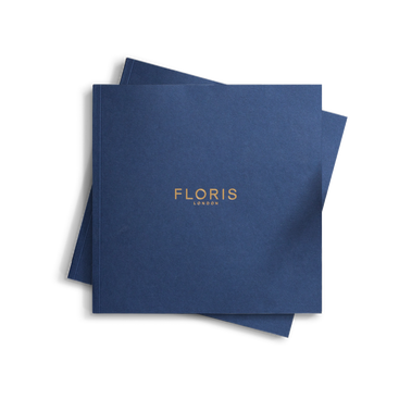 A square-shaped booklet with a navy blue cover featuring the gold-embossed text 'FLORIS LONDON' cantered on the front.
