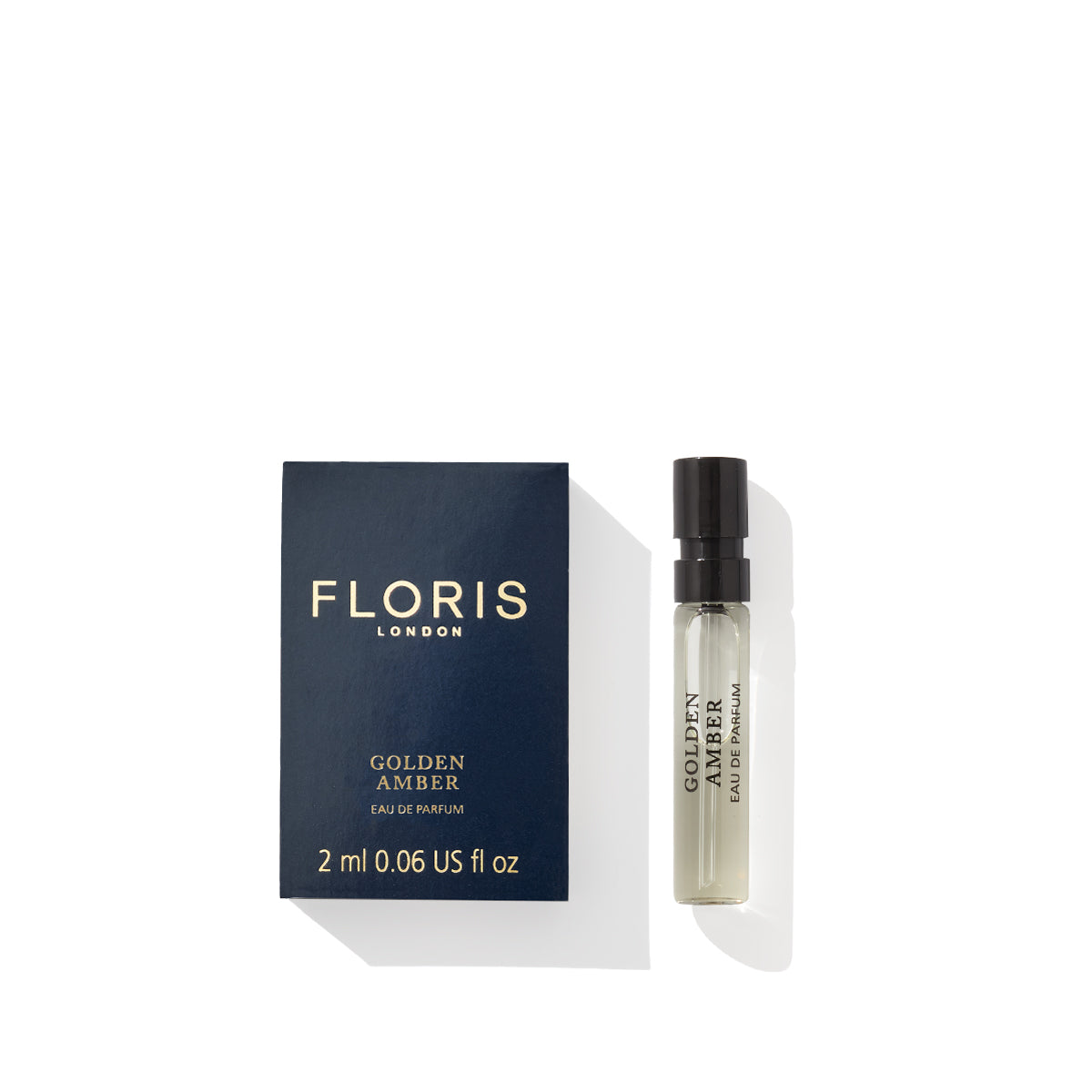 A 2 ml bottle of Floris London's Golden Amber - Eau de Parfum, vegan and elegantly encased, sits next to its dark blue box adorned with gold lettering.