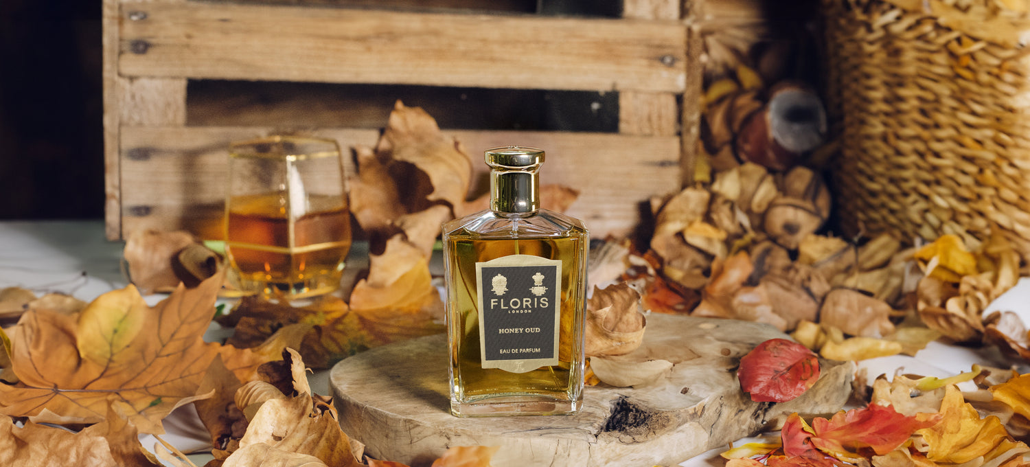 A bottle of 'Honey Oud' surrounded by autumn foliage. 