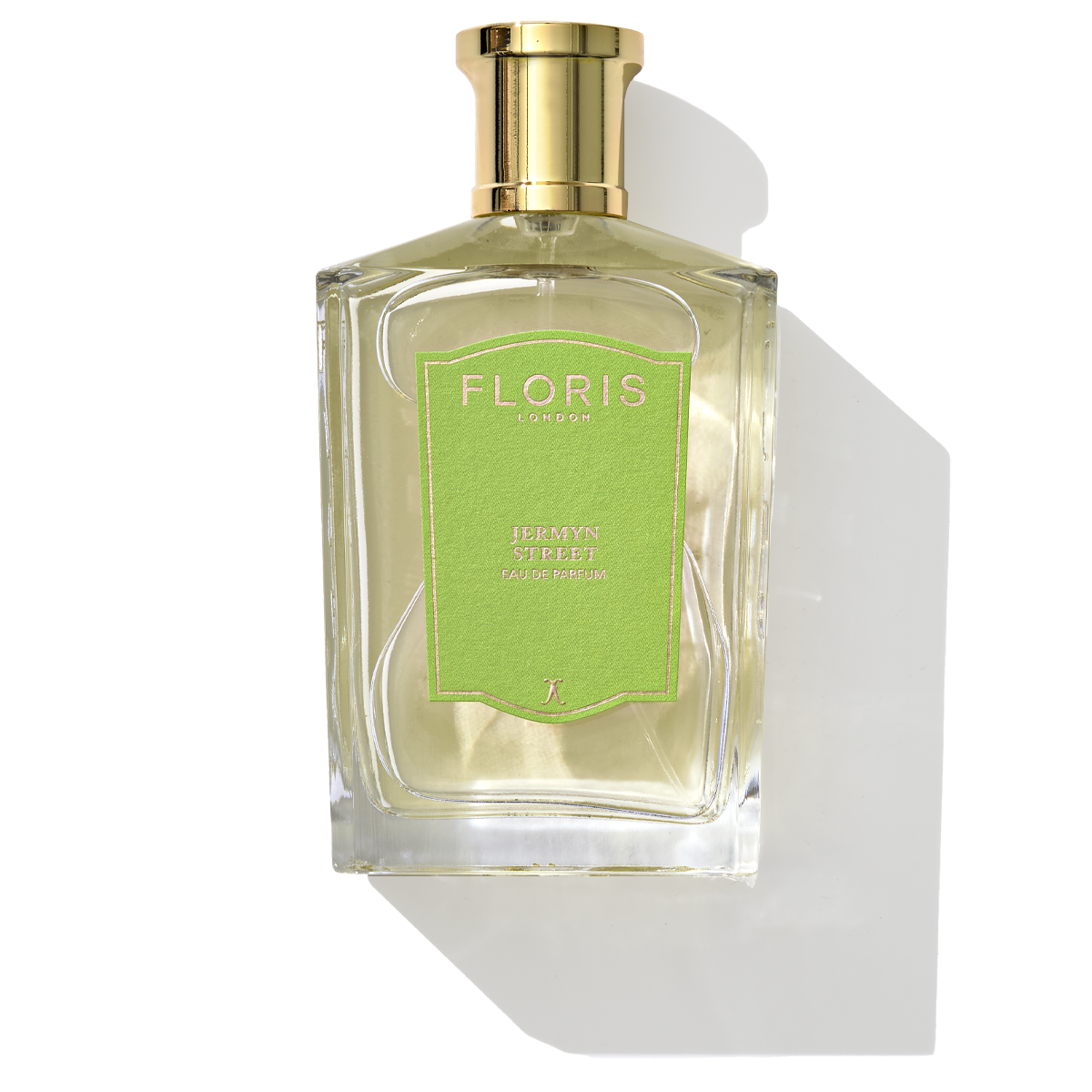 A bottle of Floris London's Jermyn Street - Eau de Parfum, adorned with a gold cap and a green label, casting a shadow. Its captivating fragrance features notes of vetiver.