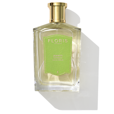 A bottle of Floris London's Jermyn Street - Eau de Parfum, adorned with a gold cap and a green label, casting a shadow. Its captivating fragrance features notes of vetiver.