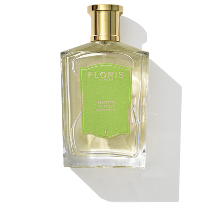 A bottle of Floris London's Jermyn Street - Eau de Parfum, adorned with a gold cap and a green label, casting a shadow. Its captivating fragrance features notes of vetiver.