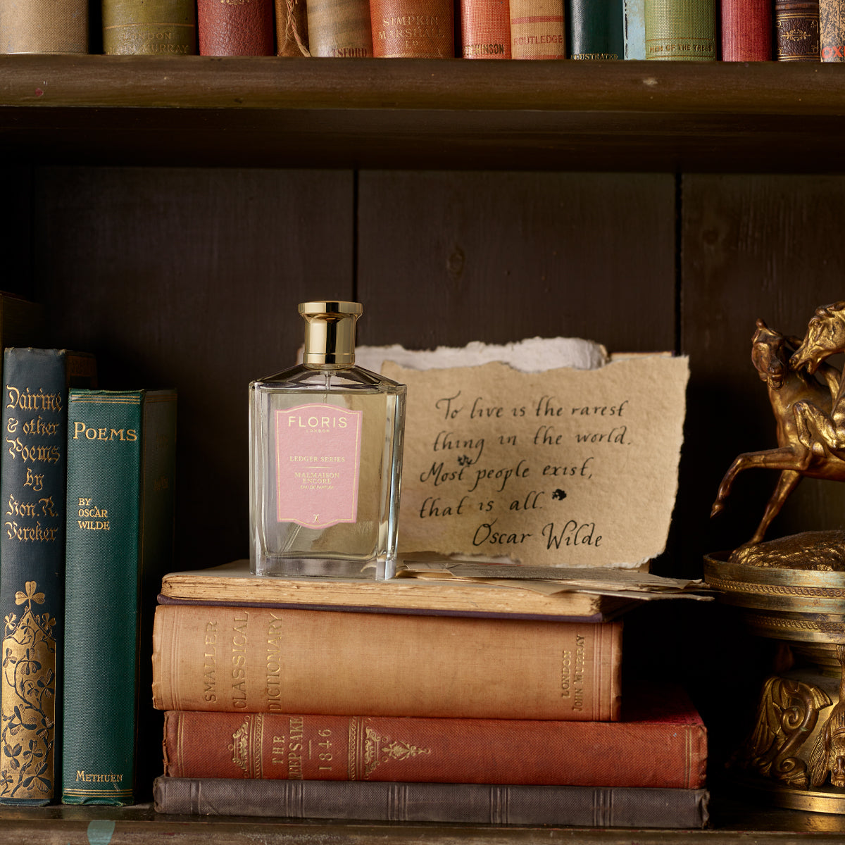 A captivating allure graces the shelves: Floris London's Malmaison Encore, a floral oriental fragrance, with books and an Oscar Wilde quote nearby.