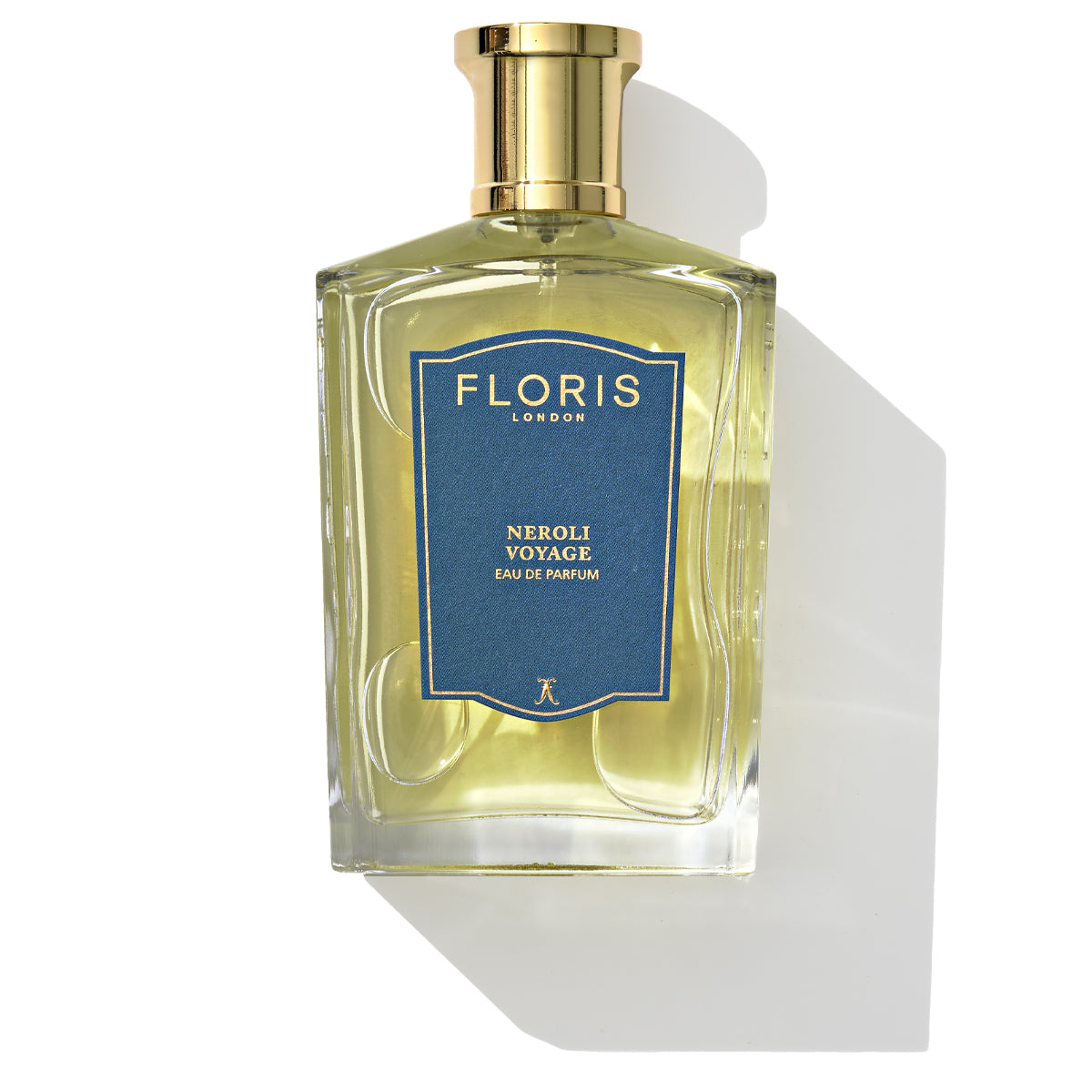 A bottle of Neroli Voyage - Eau de Parfum by Floris London, adorned with a blue label and gold cap, rests on a white background. This exquisite fragrance delivers a refreshing citrus burst with notes of neroli.