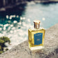 A Neroli Voyage bottle from Floris London sits on a stone ledge, with blurred sparkling water and the subtle scent of jasmine flowers in the backdrop.