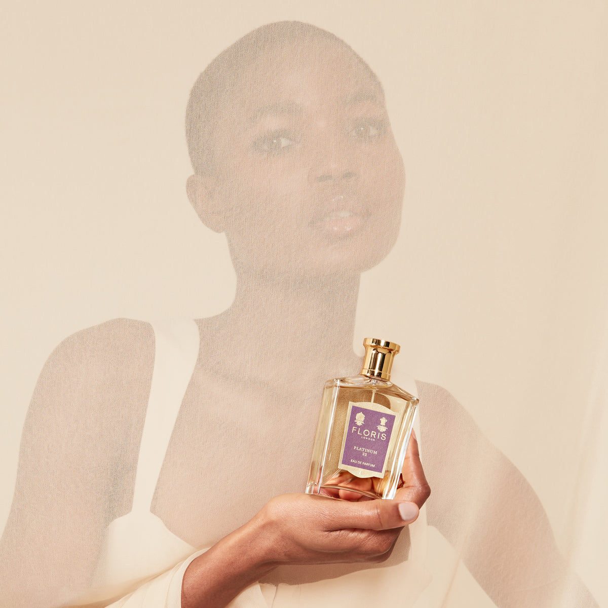 Person holding a Floris London Platinum 22 Eau de Parfum bottle against a soft beige background.