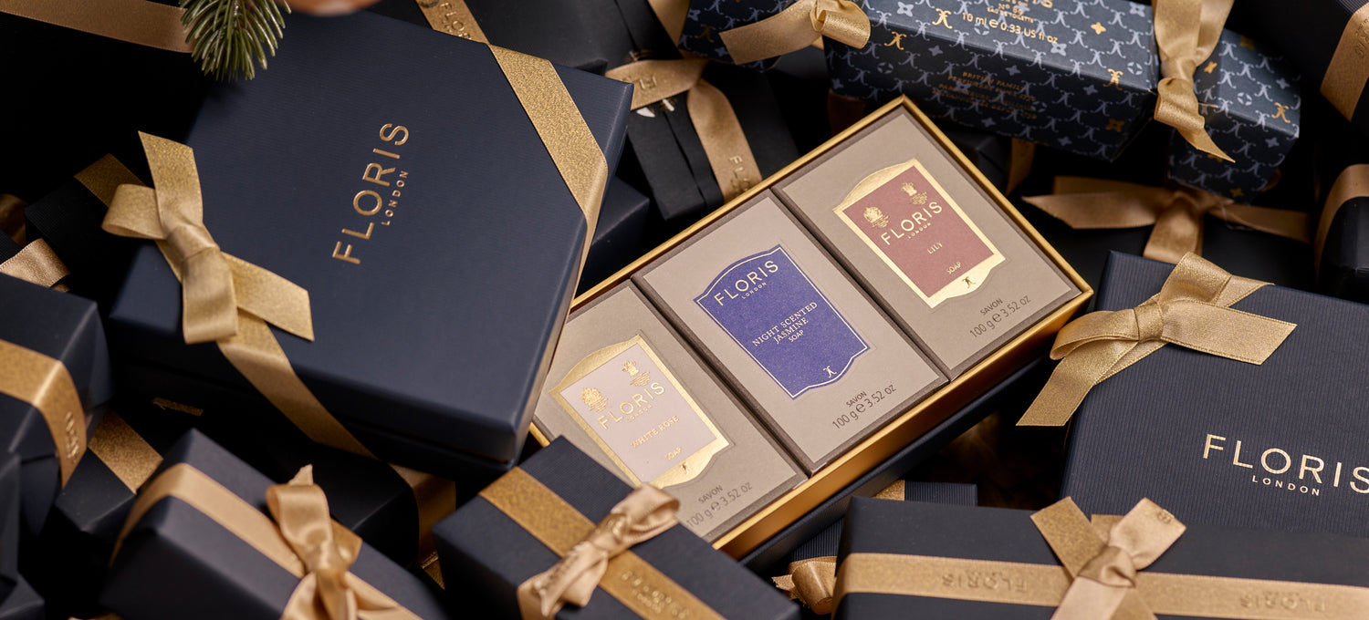 A boxed Soap Collection For Her from Floris London, featuring three exquisite soap products, nestled in-between beautifully gift wrapped presents. This luxurious gift set is perfect for the holiday season.