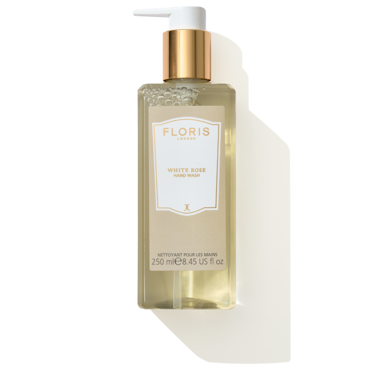 A bottle of Floris London's White Rose - Luxury Hand Wash, 250 ml, features a gold pump and an elegant beige label. Infused with coconut ingredients for a luxurious cleanse, this hand wash exudes a delightful White Rose scent.